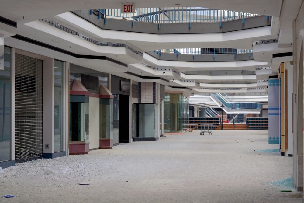 Photograph. An empty lower-level concourse in an abandoned shopping mall.