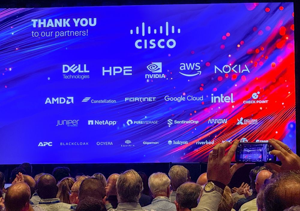 Audience members photographing a large screen at a conference 