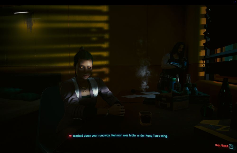Screen grab from Cyberpunk. Strips of light bleed through a blind, throwing stripes of light across the face of a woman. Her eyes emit an orange glow through the gloom, a sign she is connected to the net through cybernetic implants, her actions controlled via a distant third party. Keanu Reeves skulks in the background, leaning against a wall in a dark corner of the room.