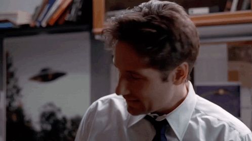 a man in a white shirt and tie is looking down at something .