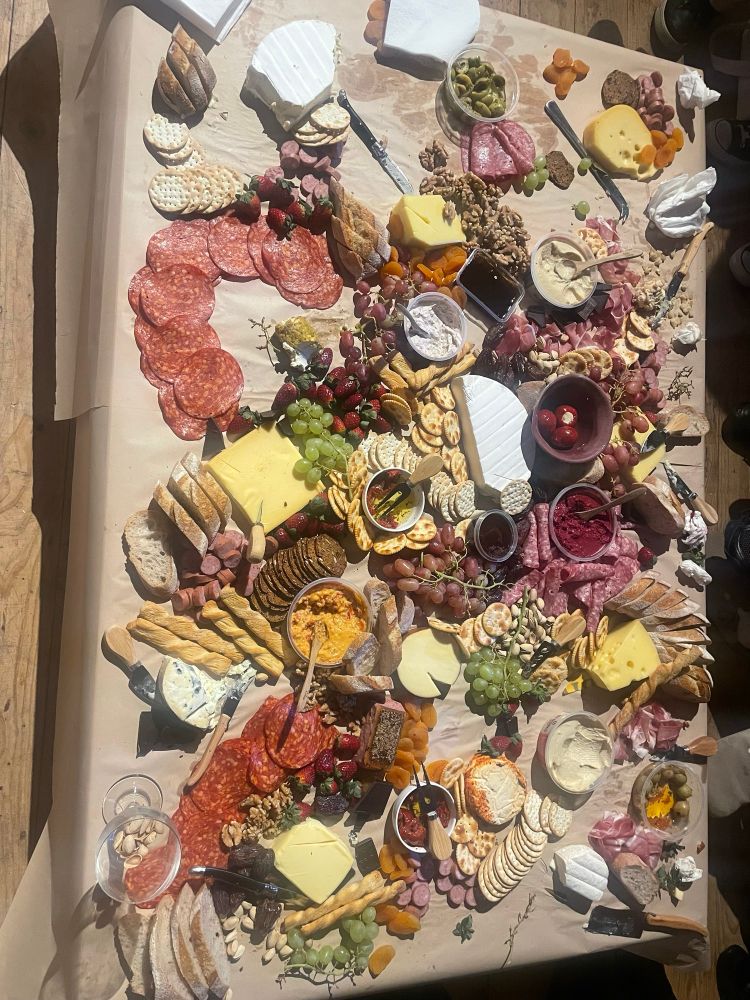 A coffee table literally covered in cheese, charcuterie, dips, crackers, bread and all the accoutrement for a great night. 