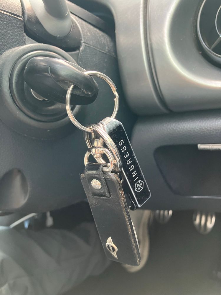車のエンジンキーがキーシリンダーに刺さっている様子　鍵にはMINIのキーホルダーとIngressの栓抜きがぶら下がっている