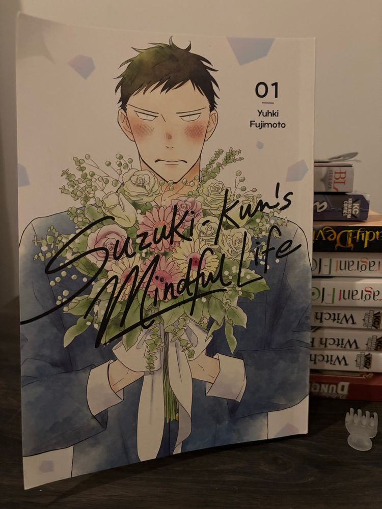 An upright copy of Suzuki-kun’s Mindful Life with the main character, Suzuki, holding a large bouquet of artfully arranged flowers. 