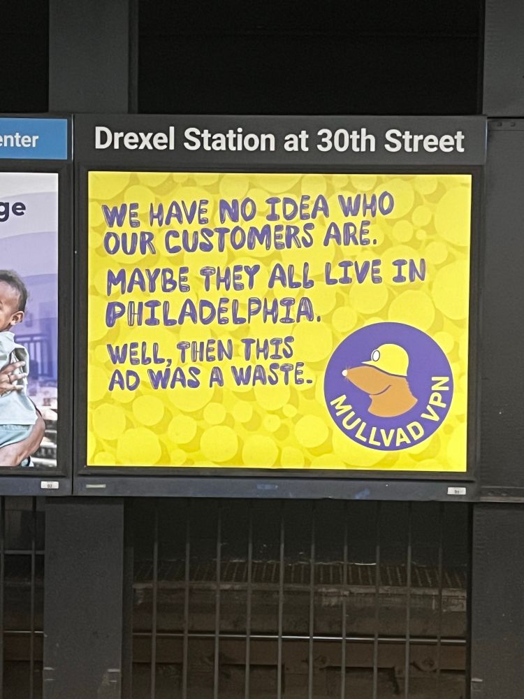 An advertisement in a subway station for Mullvad VPN, which has a yellow and purple Wario-like color scheme.