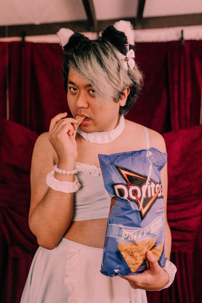 Chris wearing cat ears and a skimpier light blue maid outfit eating Cool Ranch Doritos