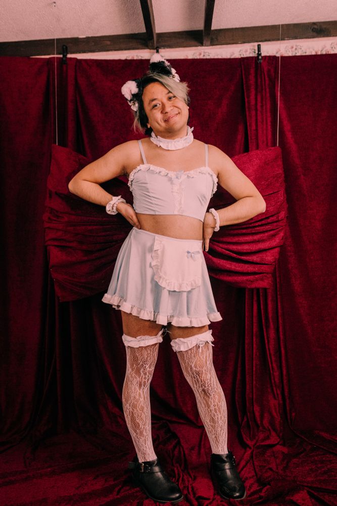 Chris posing wearing cat ears and a skimpier light blue maid outfit