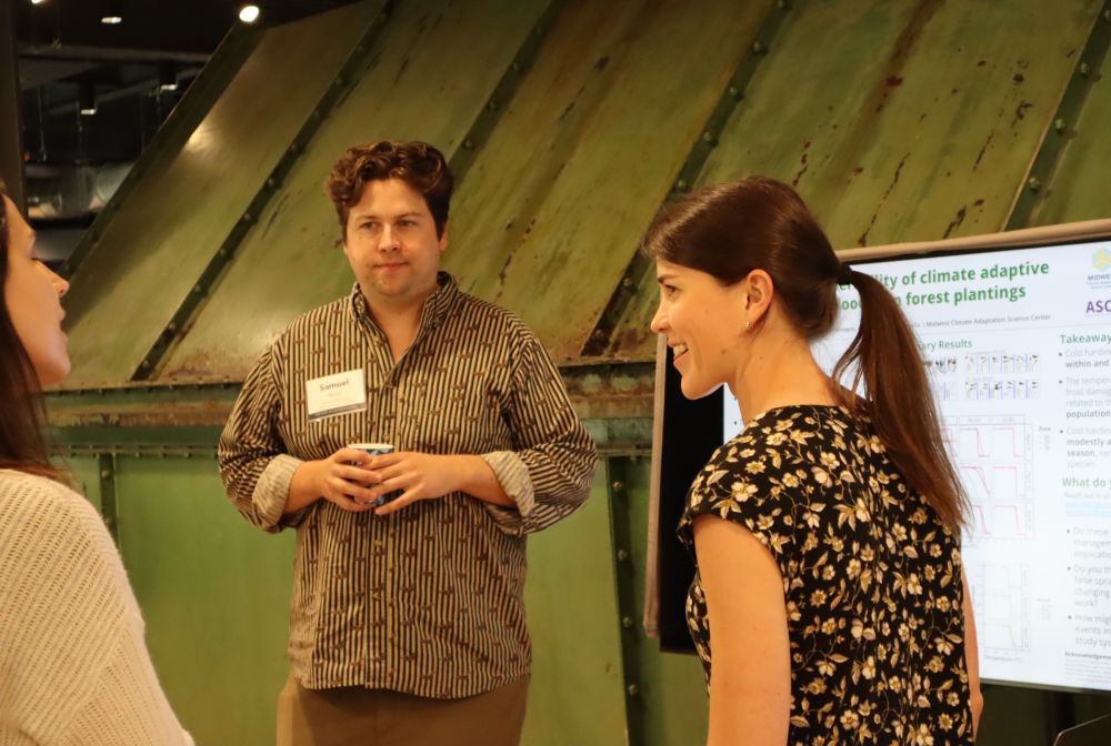 Two people smiling and standing in front of a digital research poster.