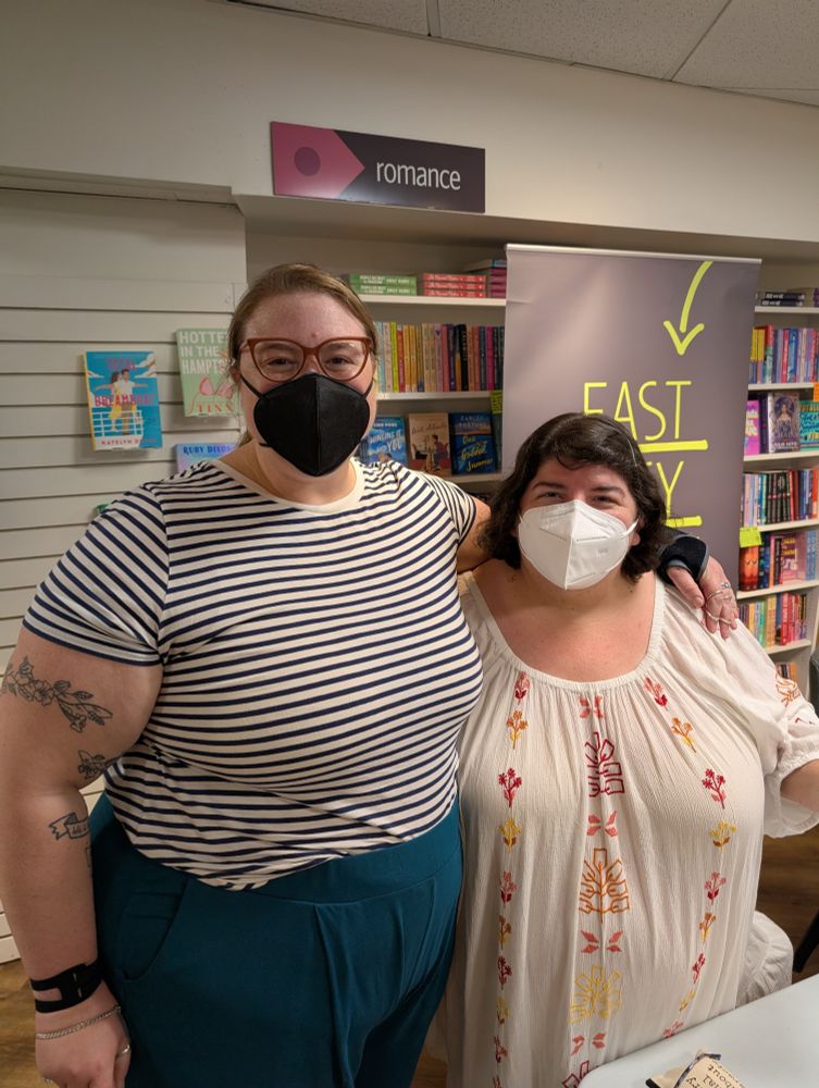 Lindsay, a white woman with a glitter cane, a striped shirt and a black facemask, and Olivia on the right, in a white and red flowers dress with a white facemask on. 