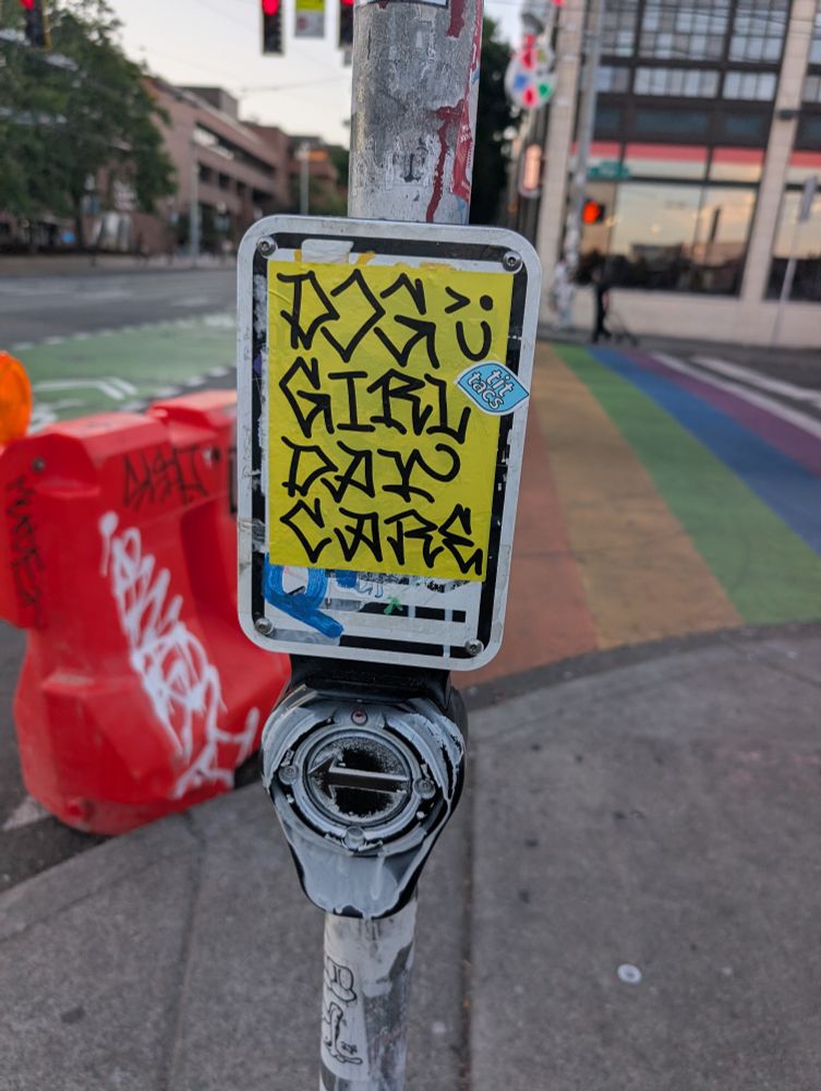 Sticker over a crosswalk indicator that reads "Dog Girl Day Care"