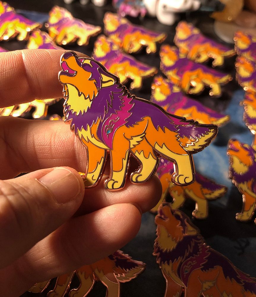 Enamel pin of a howling cartoon wolf that is pink and orange