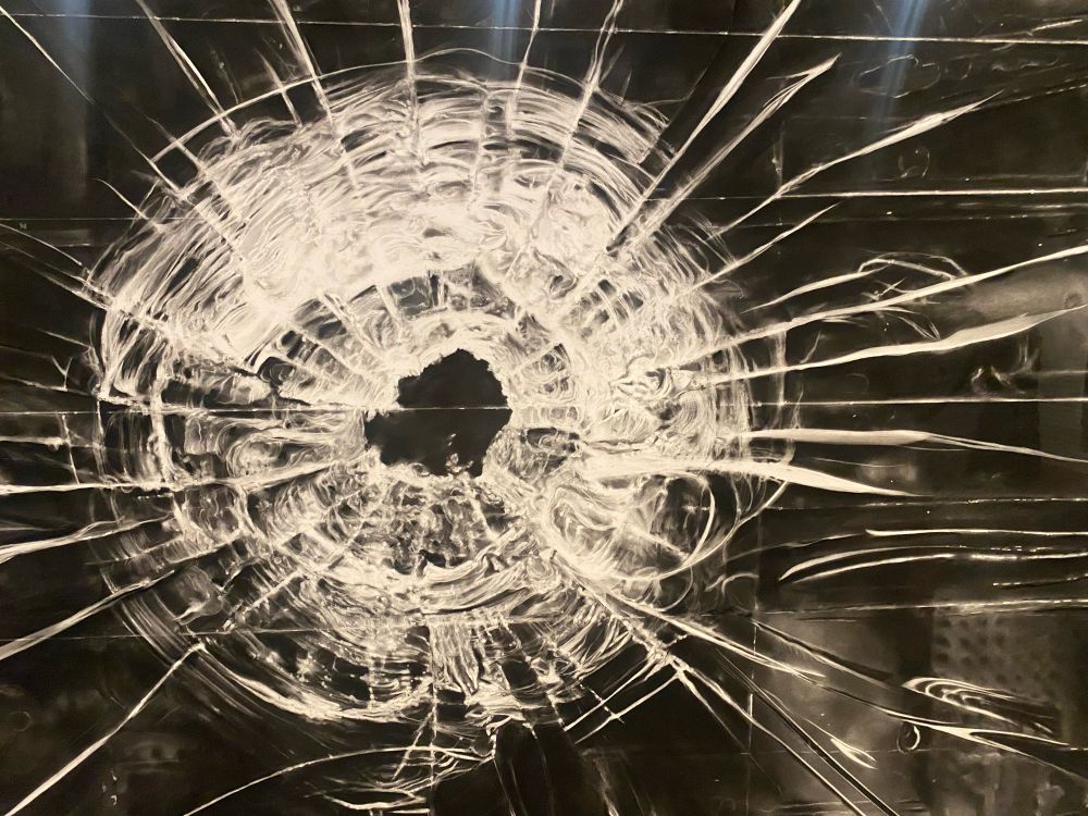 Detalj från tavla av Longo. Glasruta som genomborrats av ett skott. 

Kol på papper. 

Hela målningen cirka 2 x 4 meter

Utsnittet cirka 1 x 1 meter