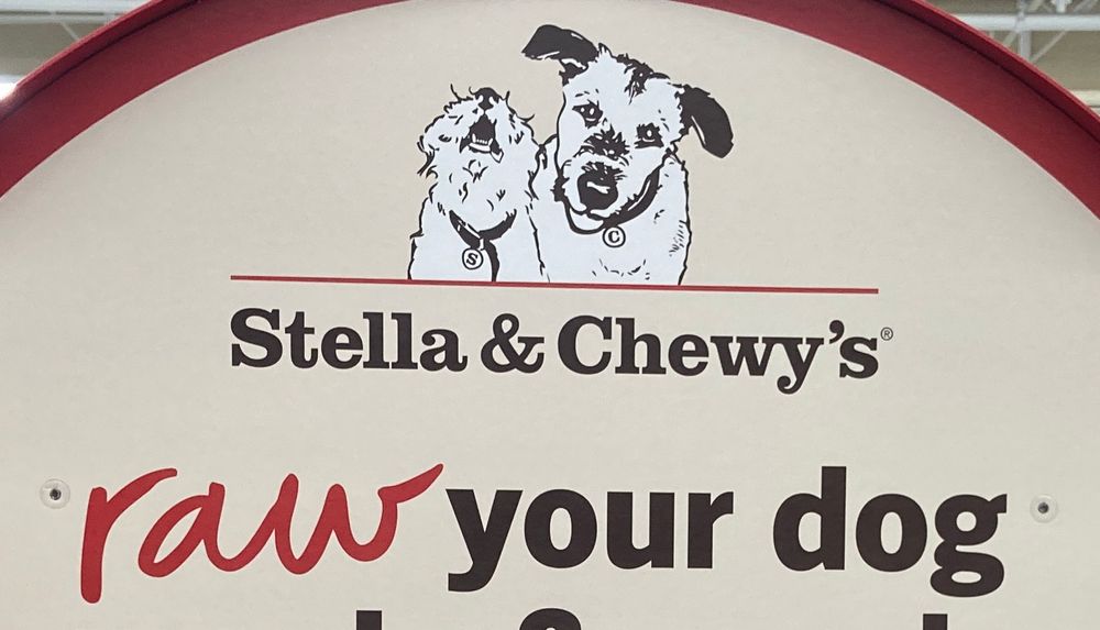 A sign with two small dogs over the name Stella & Chewy’s with the words “raw your dog”