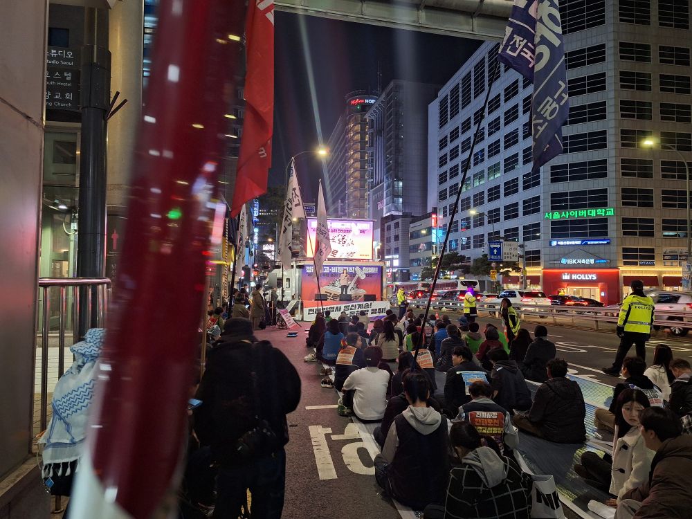 2025 근로기준법이 버린 전태일들의 행진: 전태일 열사 55주기 비정규직 전야제. 명동역 1번 출구 앞에서 철야 집회를 하는 사람들.