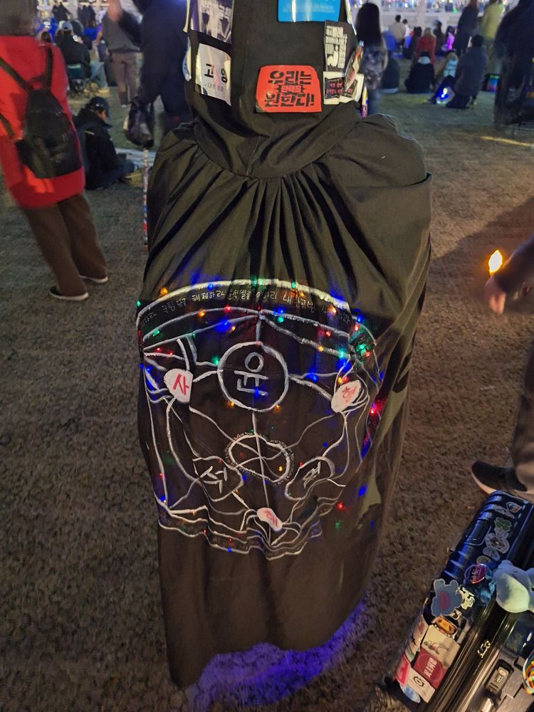 마법진이 그려진 검은 망토를 걸친 사람의 뒷모습.