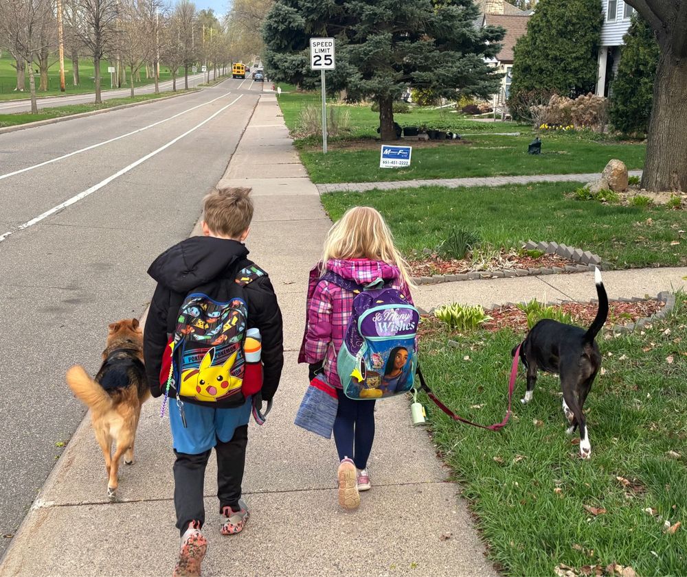 2 kids walking to school, each walking with one of their dogs 