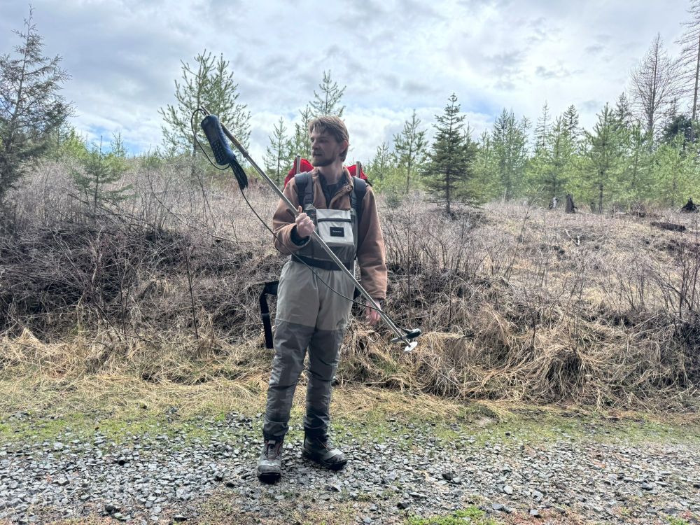 a dude in waders holding a graduated wading rod with an attached flow meter. Explaining to my colleagues how the wading rod is used to capture the total stream discharge. 