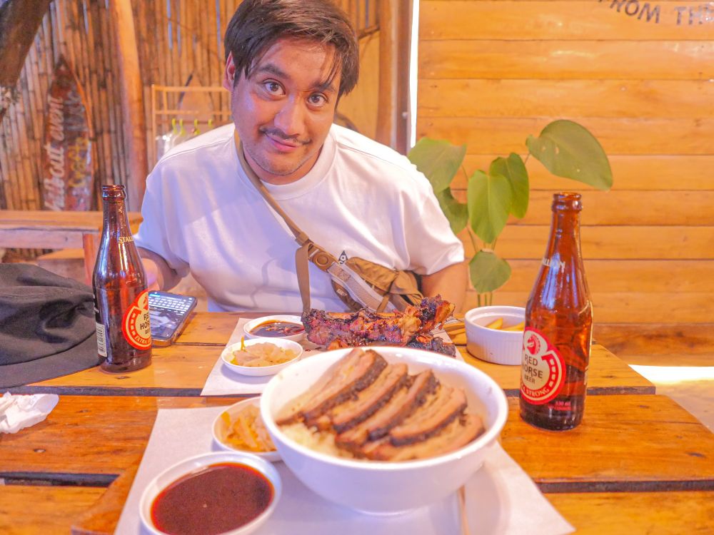 Filippinsk mann på restaurant med bbq mat og red horse øl som stirrer rett inn i kamera