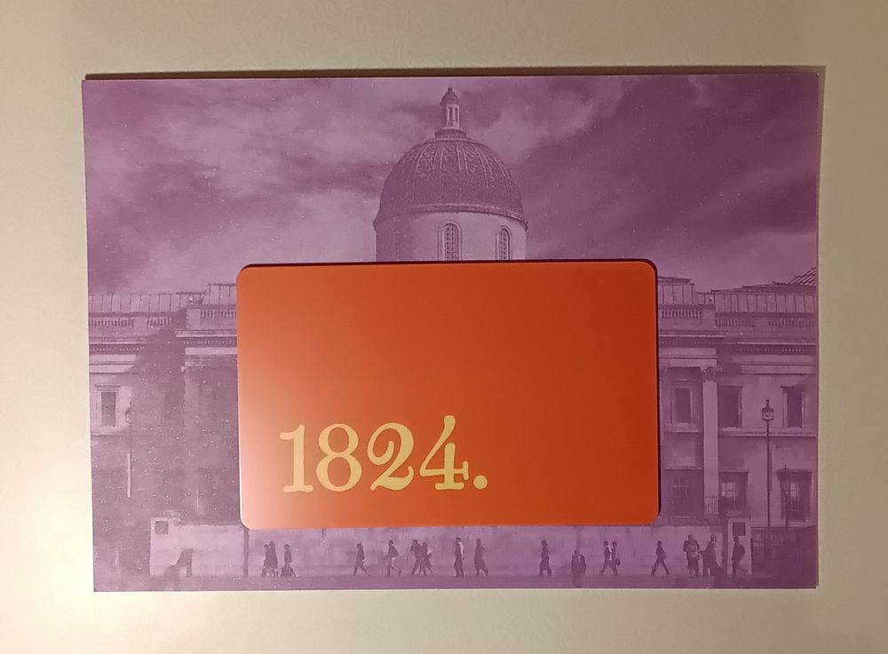 A plain orange coloured credit card-size card with 1824 and a full stop in an archaic font in yellow on it, towards the lower left hand corner, mounted on a purple-tinted photograph of the National Gallery, Trafalgar Square, London. The reverse side of the current 12 months National Gallery membership scheme admittance card as distributed by post upon renewal of subscription.