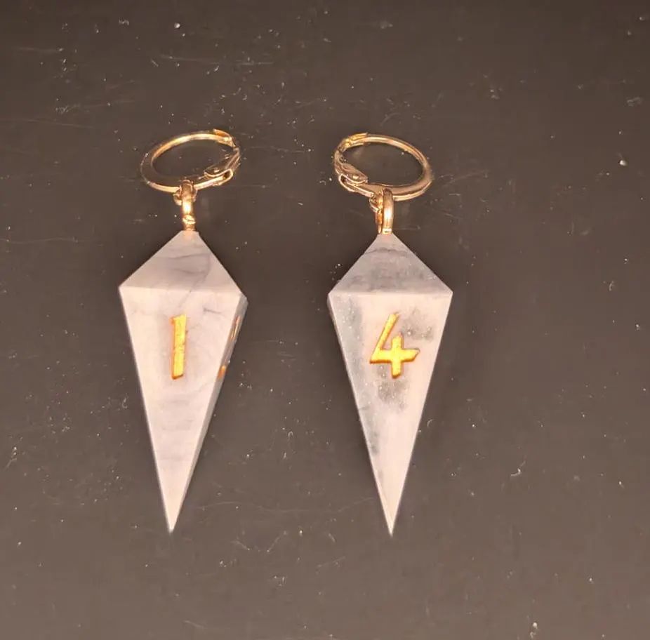 A pair of earrings made from elongated 4 sided dice, designed to look like marble