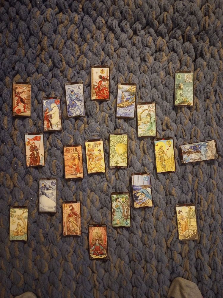 A tarot spread. There is a circle that contains the two of wands, the six of swords, the two of pentacles, the sun, the four of swords, the prince of pentacles, the emperor, the four of wands, the princess of swords, the six of wands, the moon and the king of swords. In the rightmost corner is the four of pentacles, the lower left the nine of chalices, lower right four of chalices, upper left is the seven of wands. In the center are the eight of wands, the three of chalices, and the ace of pentacles (reversed). On the right is the three of swords.