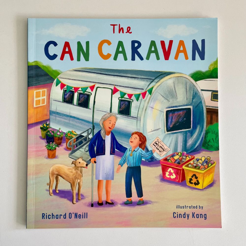 The Can Caravan book cover with a metal made caravan home, recycling boxes outside and the owner with her dog and young designer Janie.