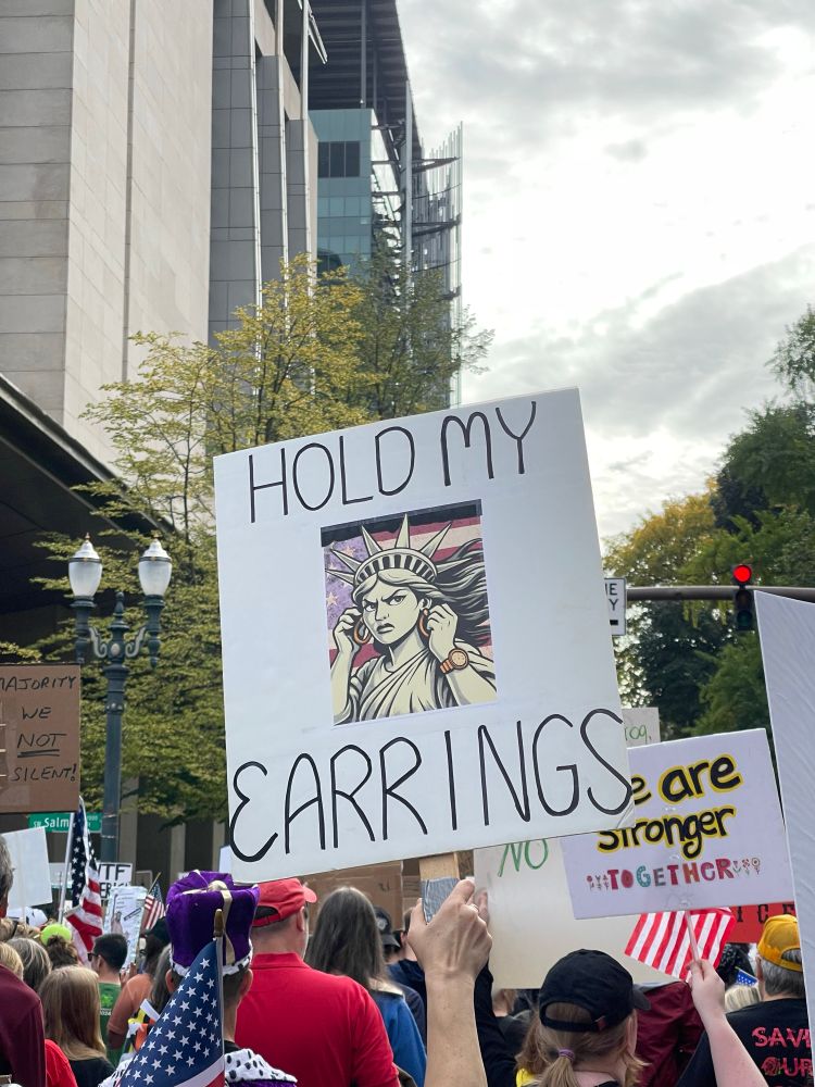 Sign showing the Statue of Liberty saying “Hold My Earrings”