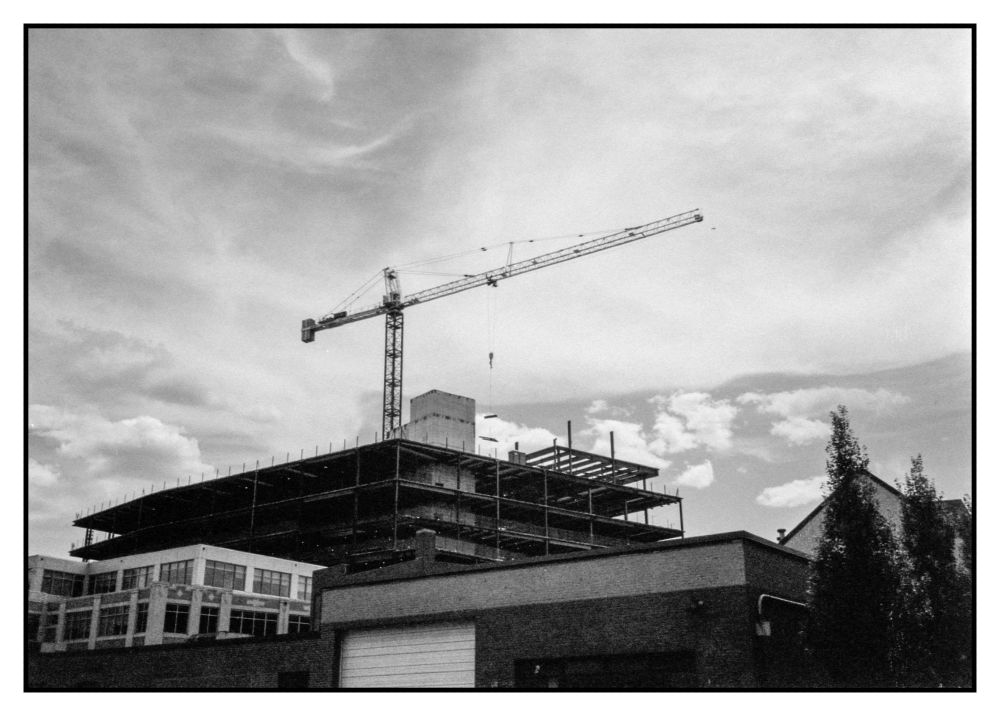 Half-frame photo of the large crane helping with the construction of Brown University's new integrated life sciences building with wispy clouds in the sky