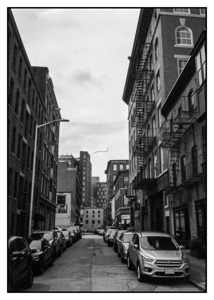 Down the one way side street, parked full of cars, looking at the same building in the other photo at the very end of the street, and a whisker of black from the film that I'm only noticing now. 