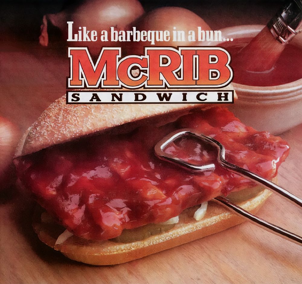 McRib advertising.  Saucy pork sandwich on a bun with onions and pickles.