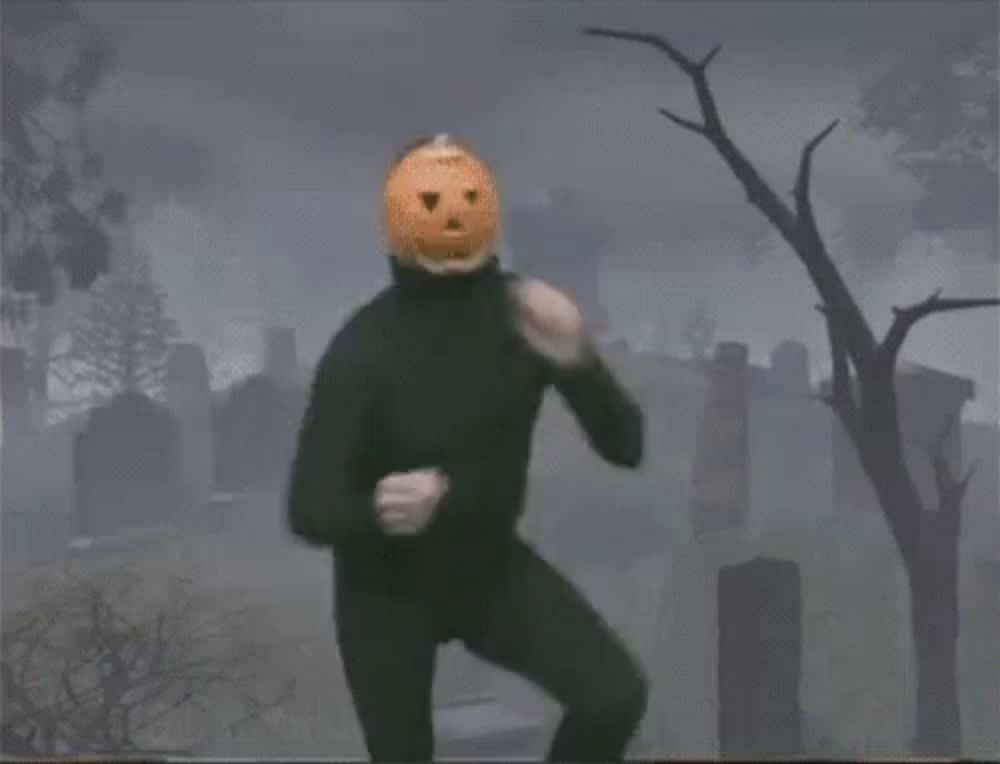 a man with a pumpkin on his head is standing in a cemetery