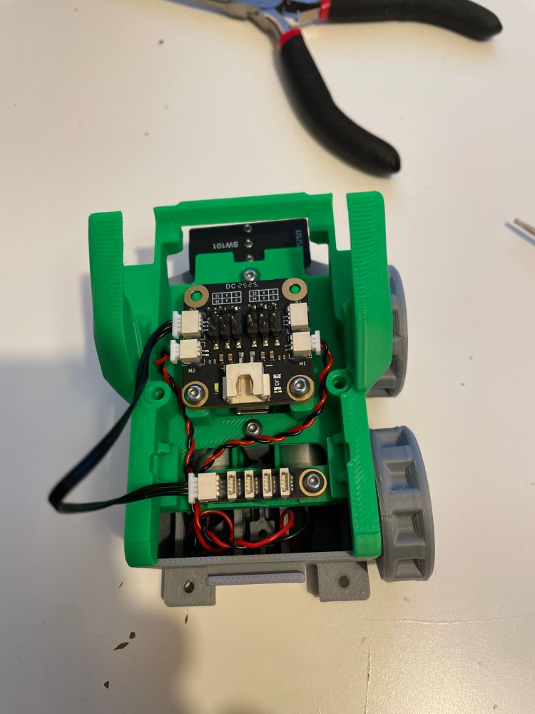 Cyberbrick forklift partially assembled. Wheels (or sprockets) are on one side, but not the other. Some electronics are in place.