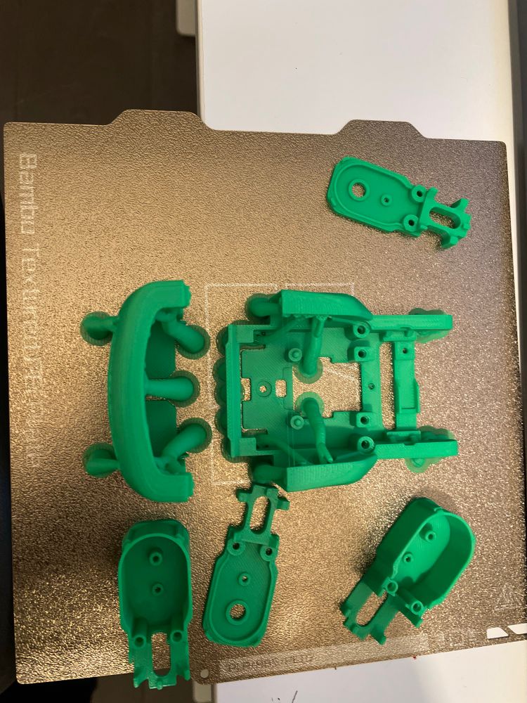 Cyberbrick forklift plate one printed on an a1 mini in green PLA. The parts are partially slid off the bed as I got impatient before taking the photo.