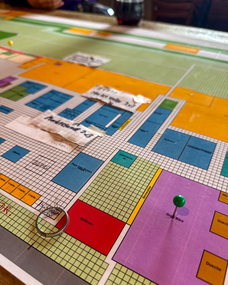 Ein buntes Spielfeld mit einer Nadel darauf.