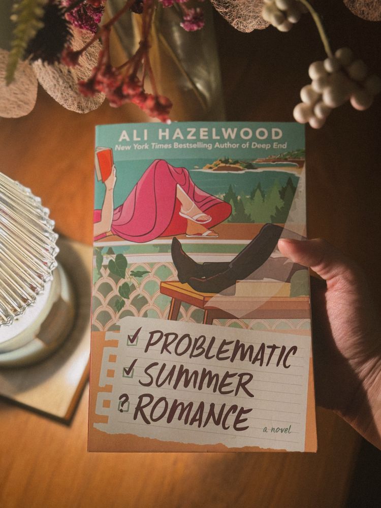 Holding up the book Problematic Summer Romance by Ali Hazelwood