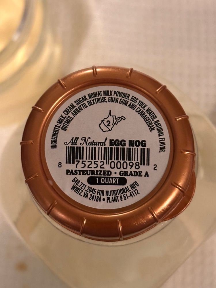 A gold rimmed bottle cap with the ingredients list, the outline of the state of West Virginia (with the number “2” inside,) “All natural egg nog,” a bar code, “Pasteurized Grade A,”  “1 Quart,” “540-771-2045 for nutritional info,” “Wirtz, VA,” and “Plant #51-4112.”