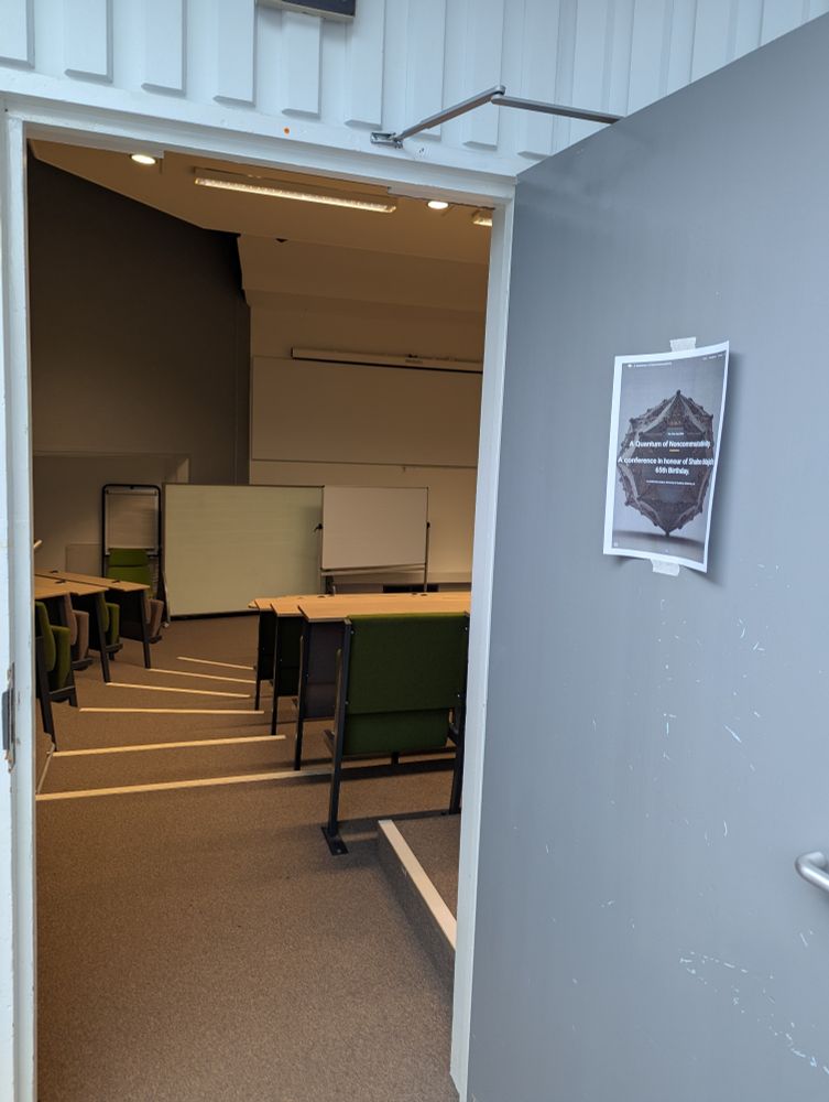 An open door with the conference poster on, with a view into a lecture theatre.