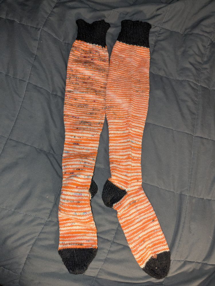 Orange and white striped, speckled socks with black heel, toe and cuff.