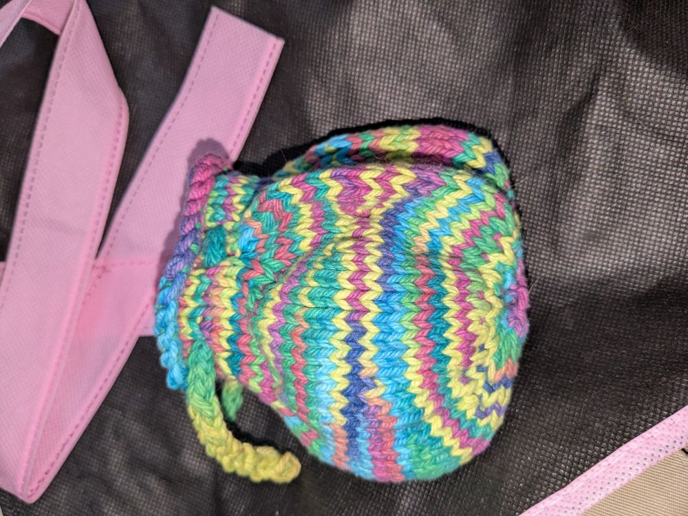 Side view of a small knit rainbow money bag.