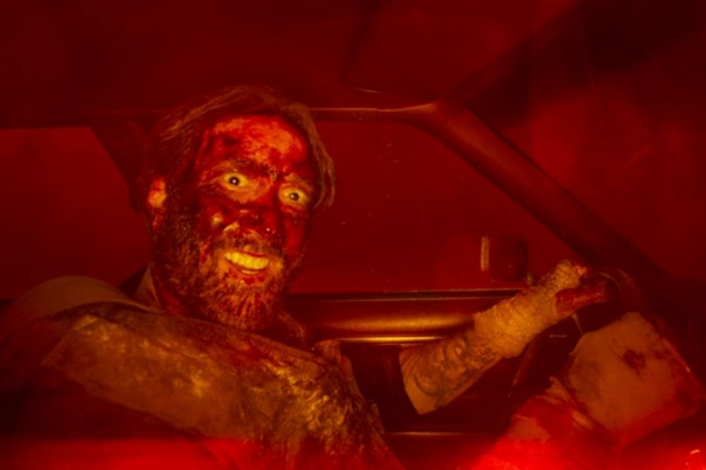 A still from the film "Mandy" (2018), with Nic Cage smiling into the camera.