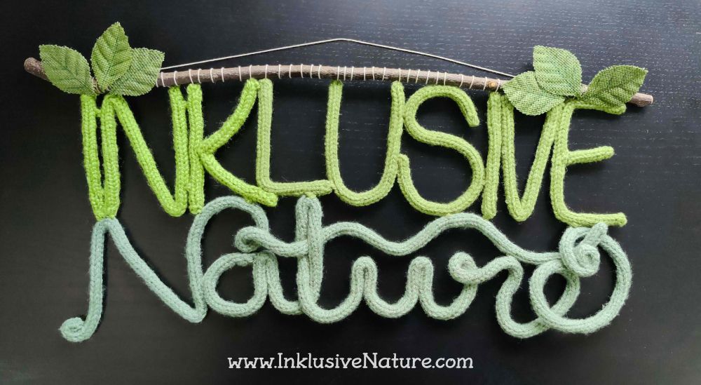 Photo of a sign made out of knitted letters reading Inklusive Nature
