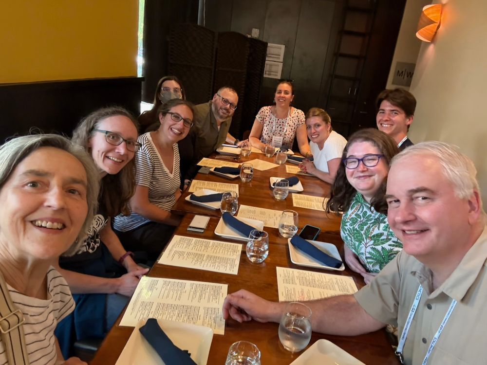 A group of 10 people sitting at a restaurant with menus, smiling for the camera. Current and former Greenwald lab members. 