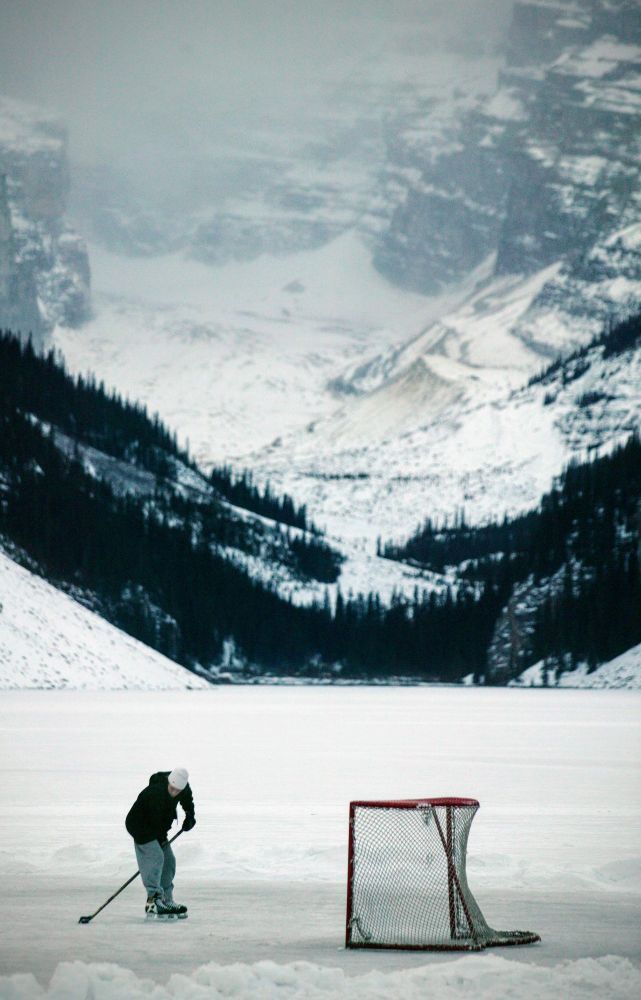 A person playing hockey on a lake in Rocky Mountain, Lake Louise.