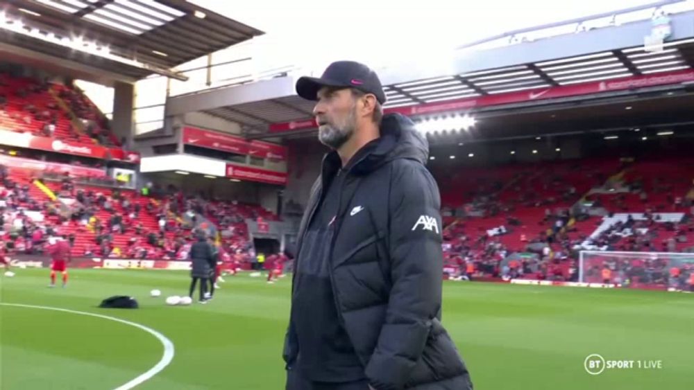 a man stands on a soccer field wearing a jacket that says ' axa ' on the side