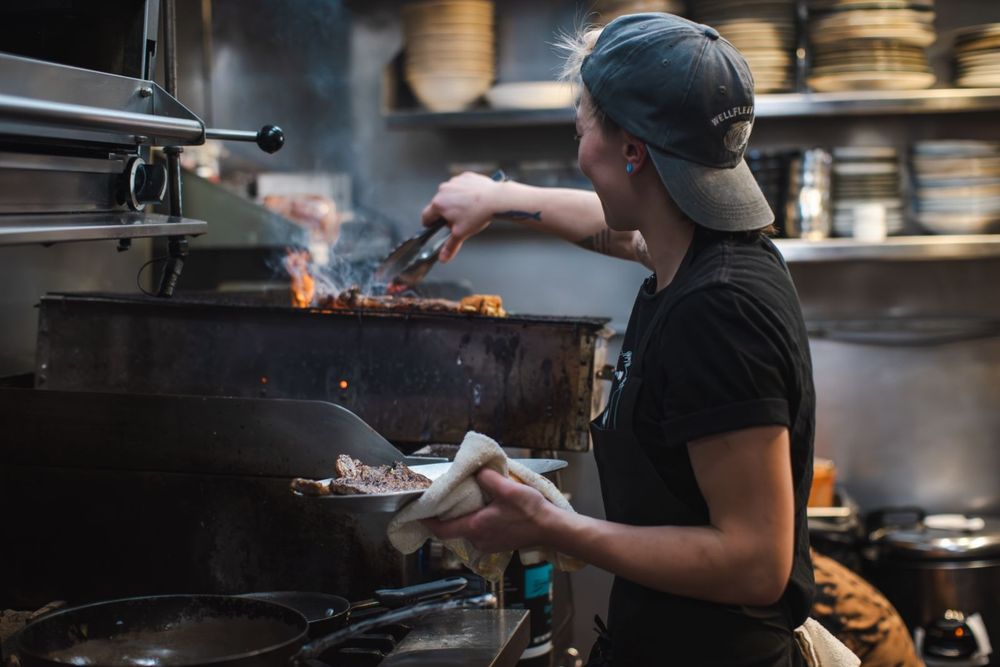 incredible babe picking up fold from a charcoal grill with tongs