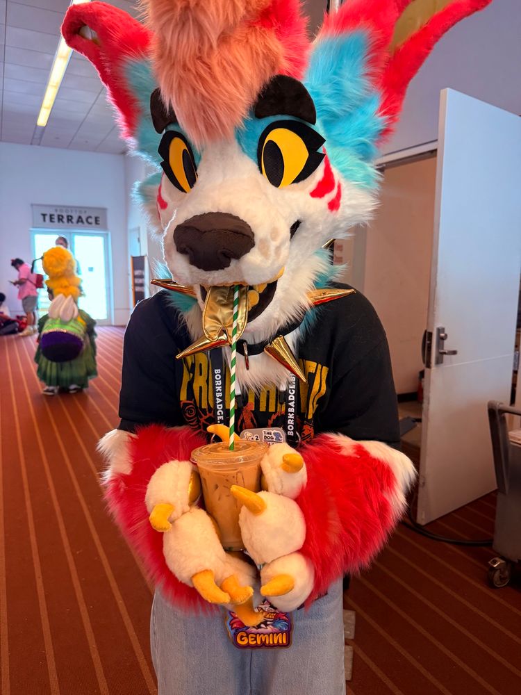 A picture of me in my Gemini Jackal partial drinking an iced latte from a very long straw, so I can sip my drink while wearing my fursuit head!
