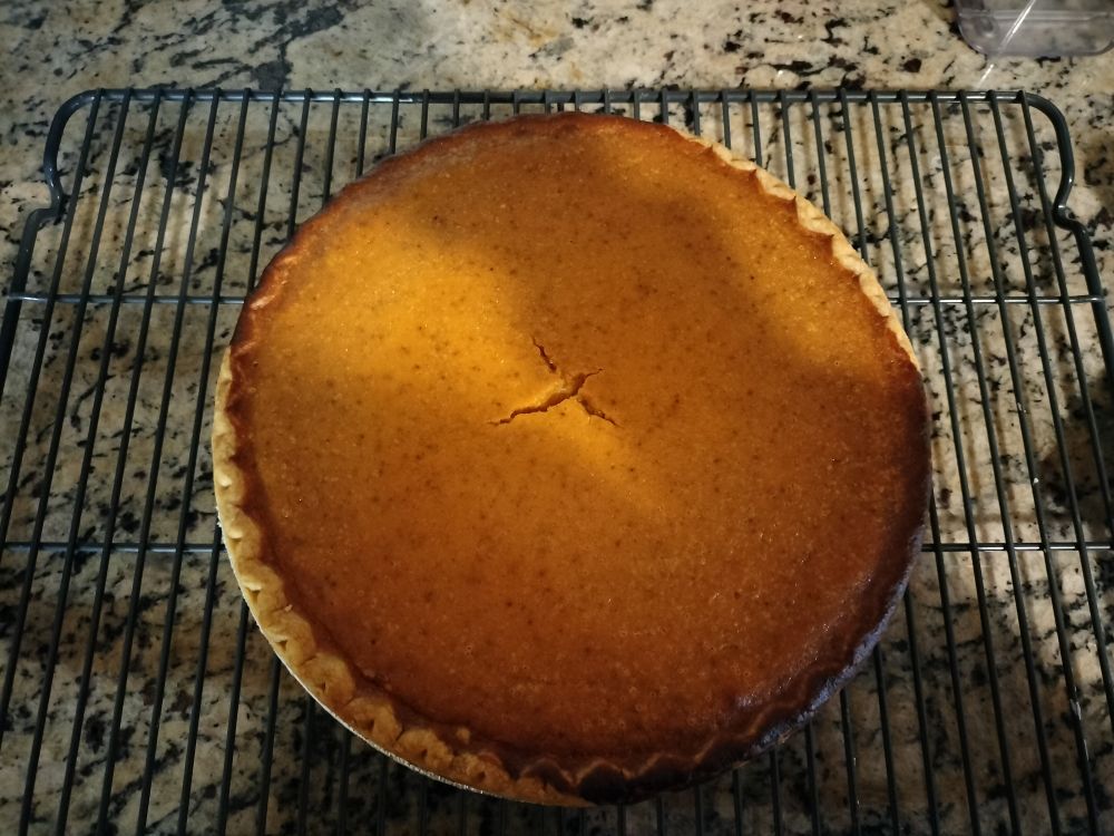A pumpkin pie cooling on a baking rack