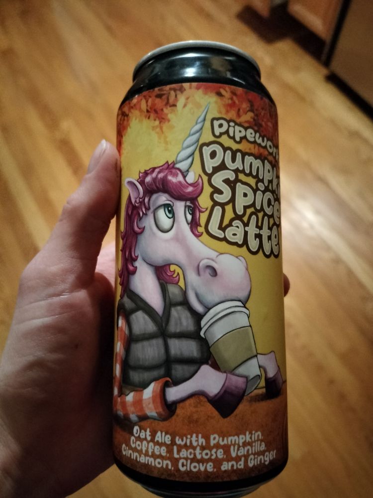 A can of Pipeworks' Pumpkin Spice Latte beer. The packaging depicts a pink unicorn in a vest and flannel shirt drinking a cup of coffee. The description at the bottom reads "Oat Ale with Pumpkin, Coffee, Lactose, Vanilla, Cinnamon, Clove, and Ginger"
