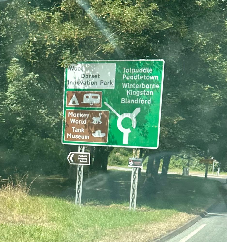 A road sign. The left turn at the roundabout leads to Monkey World and the Tank Museum. 