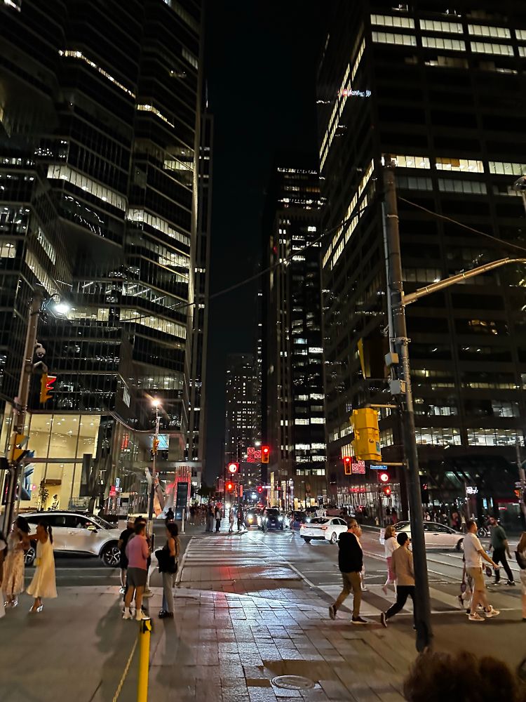 A streetscape at night in Toronto.  Looking down the street at an intersection. 