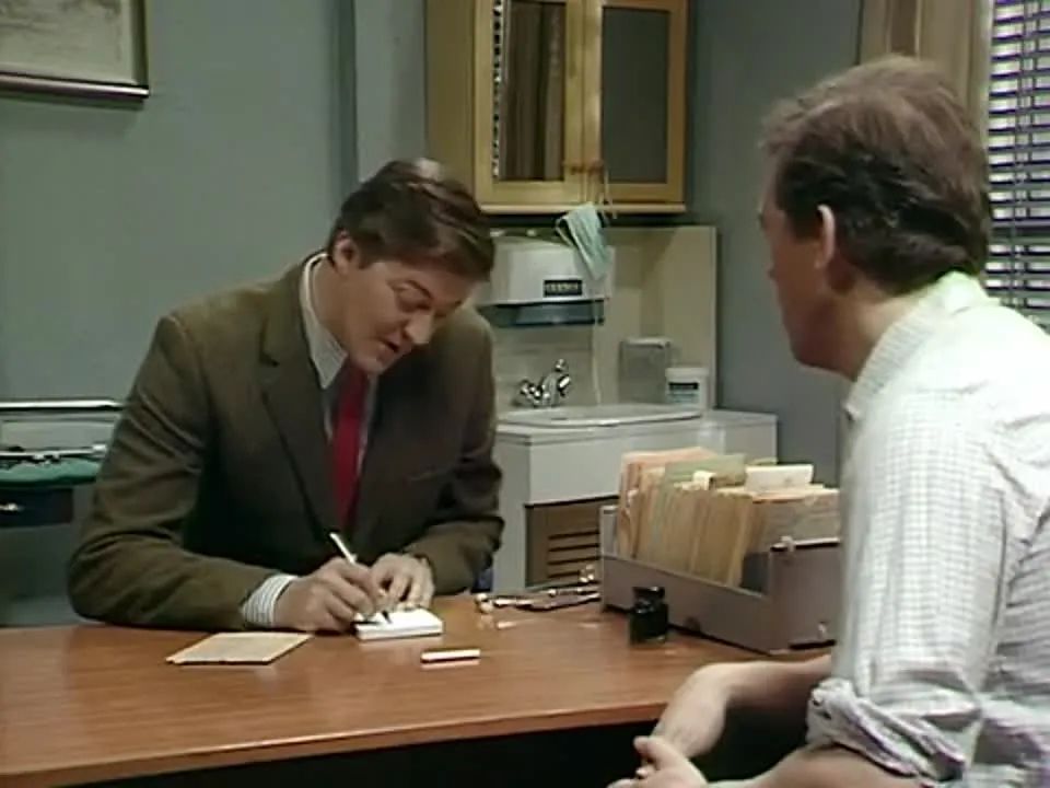 Скриншот из Шоу Фрая и Лори, где человек, сидящий в кабинете врача (он не врач), выписывает пациенту сигареты от кашля